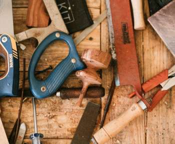 blue and black handle pliers beside brown wooden handle