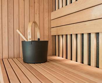 a wooden sauna with a black bucket and two wooden spoons