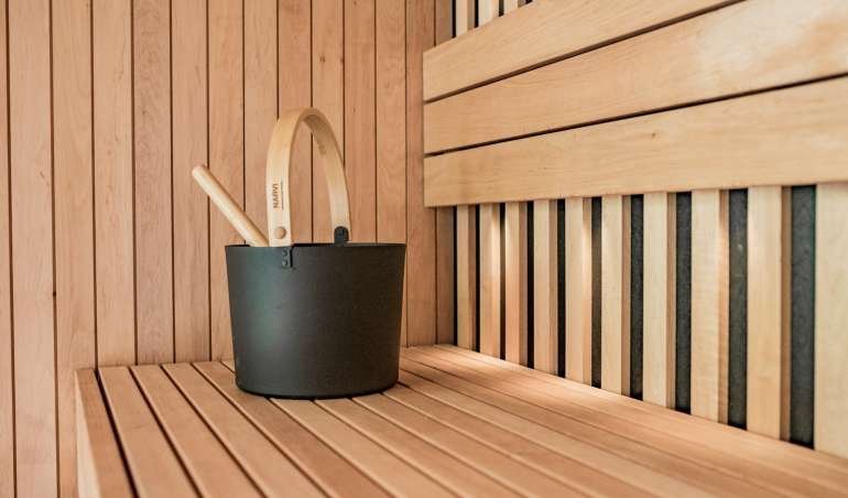 a wooden sauna with a black bucket and two wooden spoons