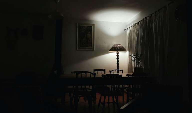a dark room with a table and a lamp